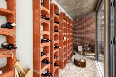 Mur en briques décoré de miroirs et d'une porte en bois sculpté, avec des canapés colorés en premier plan.