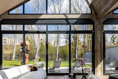 Mur en briques décoré de miroirs et d'une porte en bois sculpté, avec des canapés colorés en premier plan.