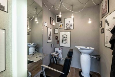 Mur en briques décoré de miroirs et d'une porte en bois sculpté, avec des canapés colorés en premier plan.
