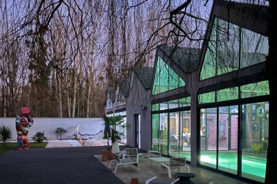 Mur en briques décoré de miroirs et d'une porte en bois sculpté, avec des canapés colorés en premier plan.