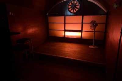 Bar en bois sombre avec comptoir équipé de crochets, étagères à verres et tableau noir affichant le menu.