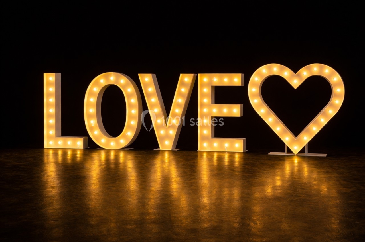 Lettres lumineuses formant le mot ’LOVE’ avec un cœur à la place du ’O’, sur un fond sombre.