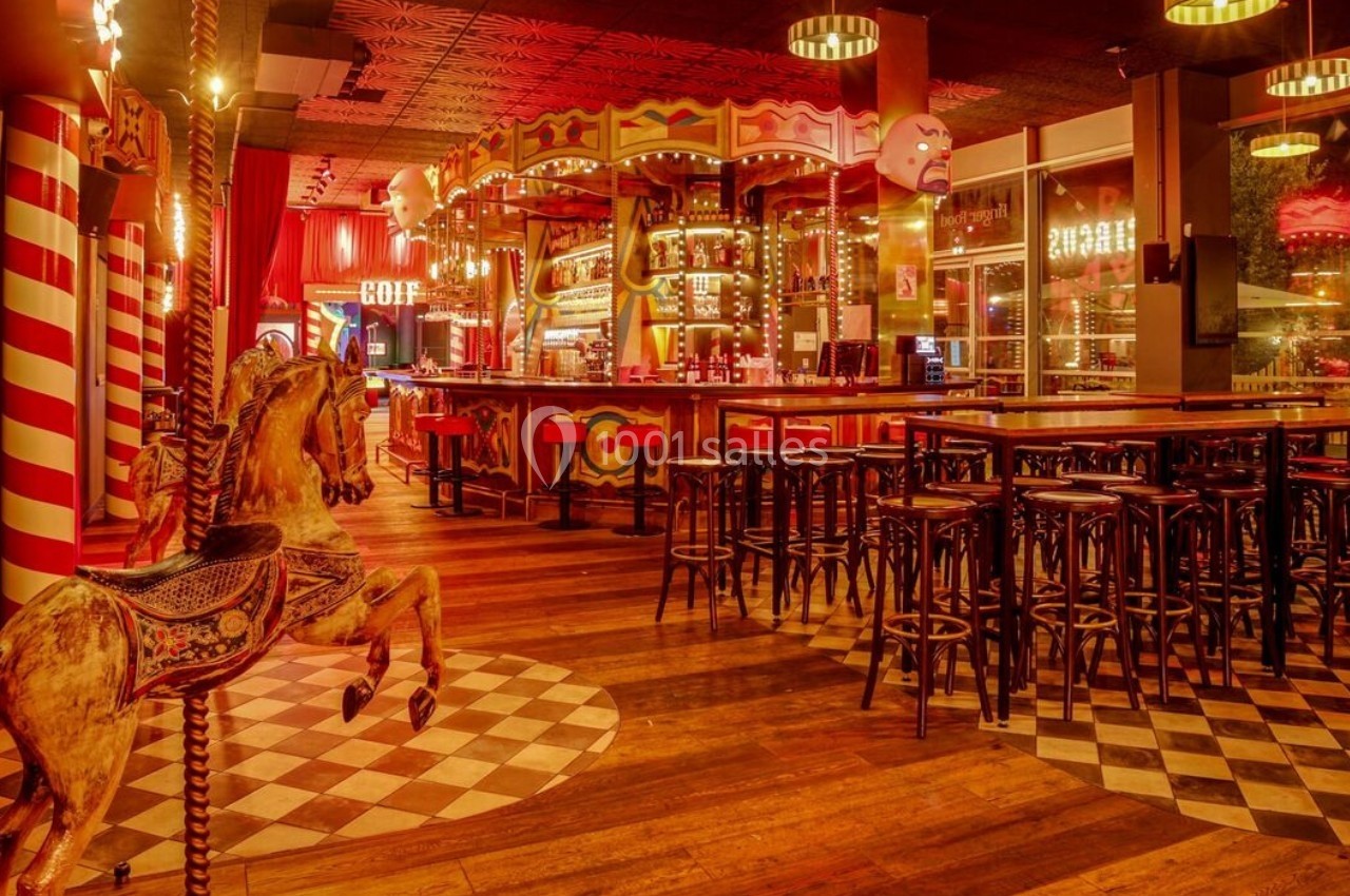 Intérieur d'un bar à thème avec décorations de manège, tabourets hauts et éclairage chaleureux.
