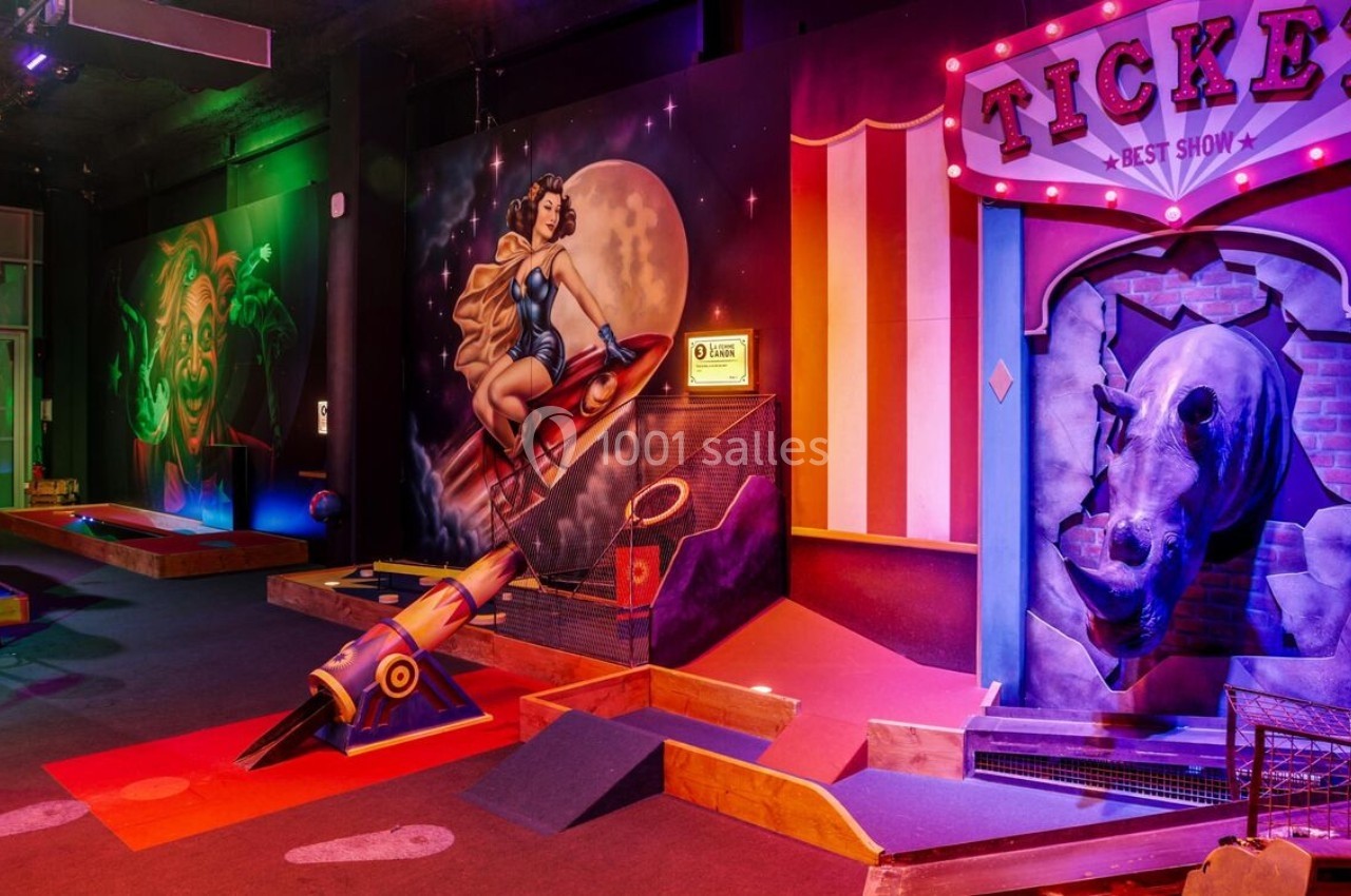 Salle de mini-golf intérieur avec décorations colorées sur le thème du cirque et de la science-fiction.