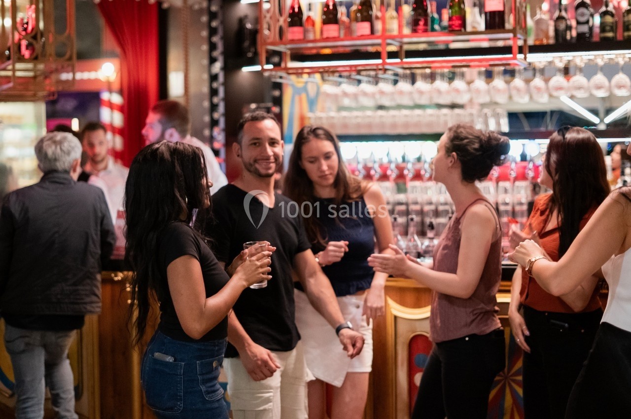 Des personnes discutent et partagent un moment convivial autour d'un bar lumineux et décoré.