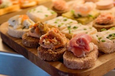 Plateaux de charcuterie avec fromage, cornichons, tranches de pain et tomates cerises, présentés sur des planches en bois.