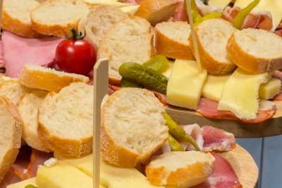 Plateaux de charcuterie avec fromage, cornichons, tranches de pain et tomates cerises, présentés sur des planches en bois.