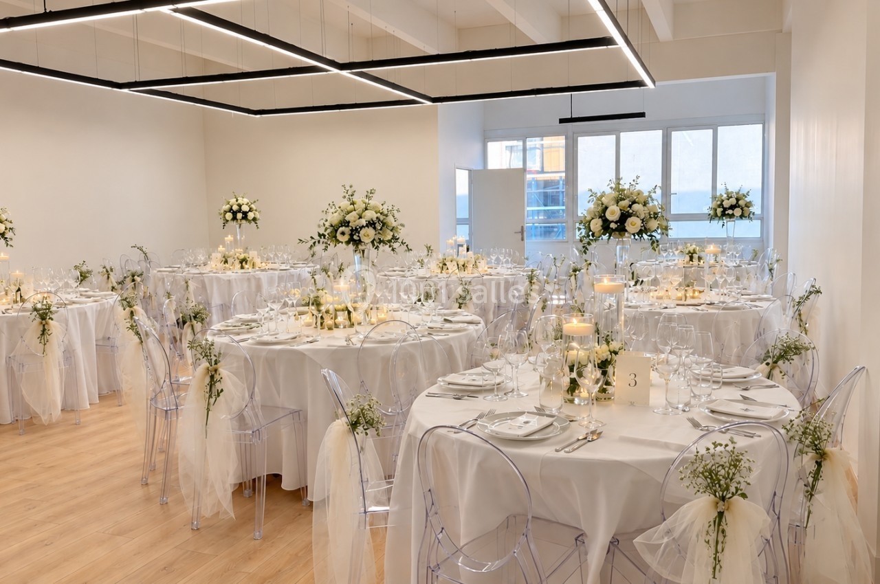Salle de réception décorée pour un mariage avec tables rondes, nappes blanches, bougies et arrangements floraux.