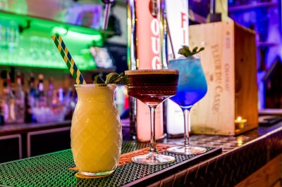 Intérieur d'un bar avec tables, chaises, murs décorés et enseigne lumineuse, ambiance chaleureuse et décontractée.