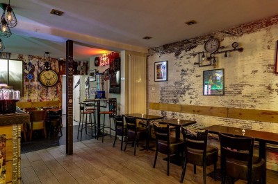 Intérieur d'un bar avec tables, chaises, murs décorés et enseigne lumineuse, ambiance chaleureuse et décontractée.