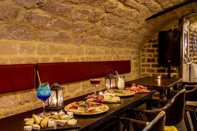 Intérieur d'un bar avec tables, chaises, murs décorés et enseigne lumineuse, ambiance chaleureuse et décontractée.