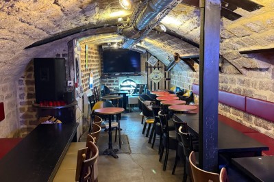 Intérieur d'un bar avec tables, chaises, murs décorés et enseigne lumineuse, ambiance chaleureuse et décontractée.