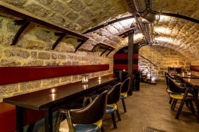 Intérieur d'un bar avec tables, chaises, murs décorés et enseigne lumineuse, ambiance chaleureuse et décontractée.