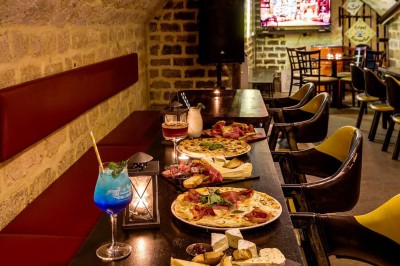 Intérieur d'un bar avec tables, chaises, murs décorés et enseigne lumineuse, ambiance chaleureuse et décontractée.