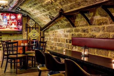 Intérieur d'un bar avec tables, chaises, murs décorés et enseigne lumineuse, ambiance chaleureuse et décontractée.