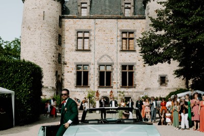 Miniature Location salle Vinzelles (Puy-de-Dôme) - Château de Sauvagnat #19 Voiture décapotable verte décorée de fleurs devant un château, avec des invités en arrière-plan.