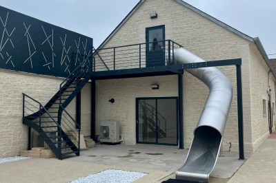 Table de ping-pong en extérieur devant un bâtiment en pierre avec une enseigne ’Le Loft de la Grange’.