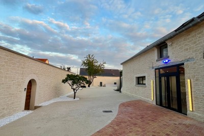 Table de ping-pong en extérieur devant un bâtiment en pierre avec une enseigne ’Le Loft de la Grange’.
