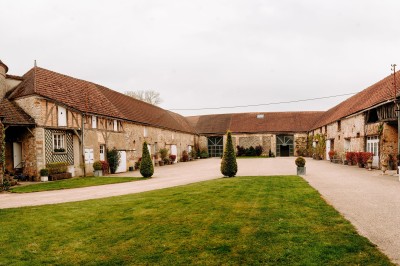Un groupe de personnes rassemblé dans la cour d'un bâtiment en pierre avec un ciel nuageux en arrière-plan.