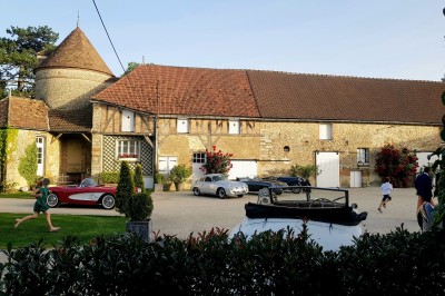 Un groupe de personnes rassemblé dans la cour d'un bâtiment en pierre avec un ciel nuageux en arrière-plan.