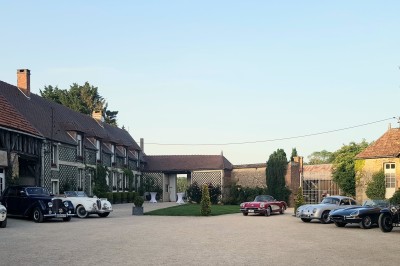 Un groupe de personnes rassemblé dans la cour d'un bâtiment en pierre avec un ciel nuageux en arrière-plan.