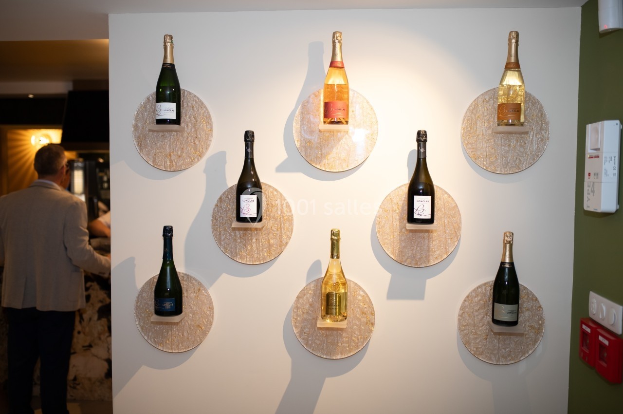Bouteilles de vin mousseux exposées sur des supports muraux circulaires dans un intérieur éclairé.