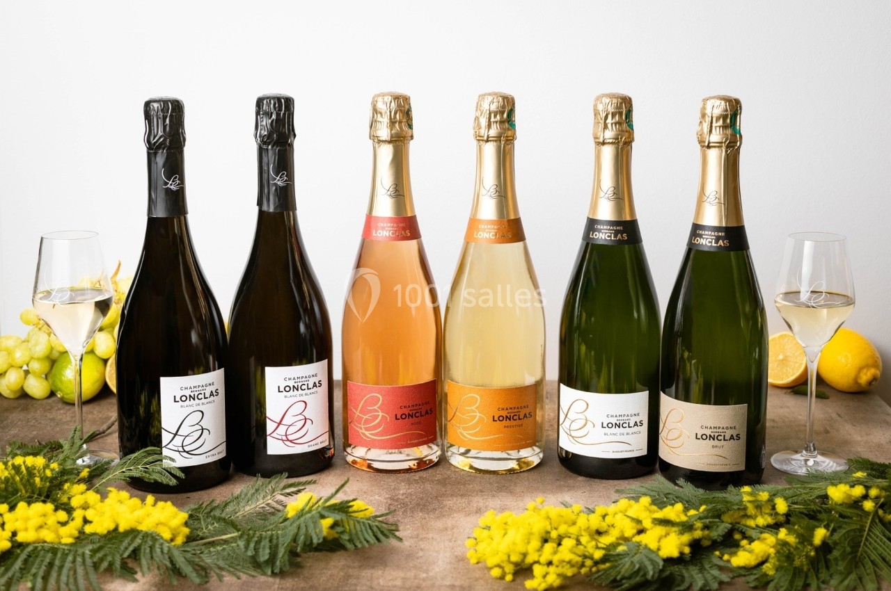 Bouteilles de champagne alignées sur une table avec des verres remplis, des grappes de raisin, des citrons et des fleurs en…