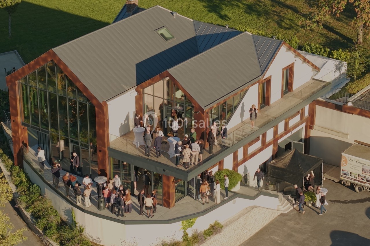 Vue aérienne d'un bâtiment moderne avec une terrasse où des personnes sont rassemblées lors d'un événement.