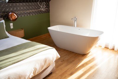 Salle de bain moderne avec deux vasques blanches, un miroir rond éclairé et une douche à paroi en verre.