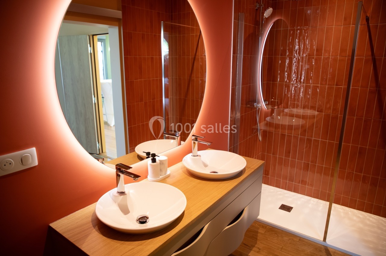 Salle de bain moderne avec deux vasques, miroir éclairé et douche à l'italienne aux parois en carreaux rouges.