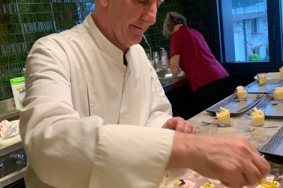 Salle de bain moderne avec deux vasques blanches, un miroir rond éclairé et une douche à paroi en verre.