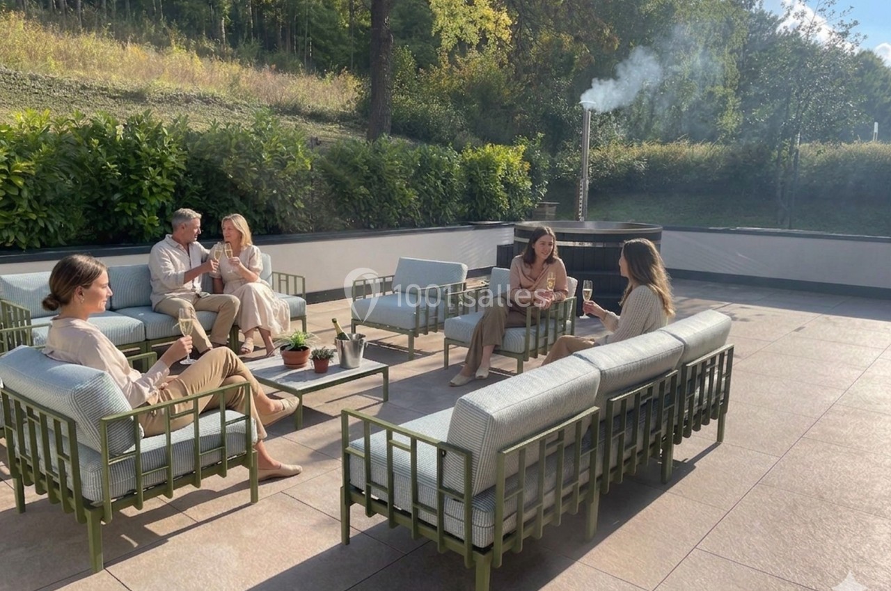 Personnes assises sur des fauteuils extérieurs, discutant et partageant un moment convivial sur une terrasse ensoleillée.
