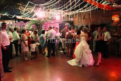 Groupe de personnes rassemblées dans une salle décorée avec des lumières et des guirlandes, lors d'une réception festive.