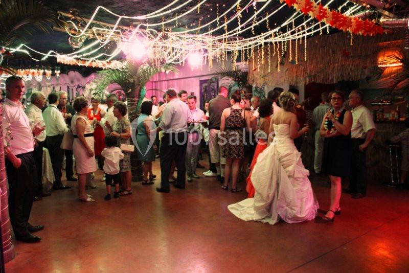 Groupe de personnes rassemblées dans une salle décorée avec des lumières et des guirlandes, lors d'une réception festive.
