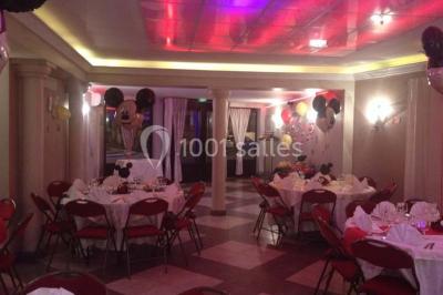 Groupe de personnes rassemblées dans une salle décorée avec des lumières et des guirlandes, lors d'une réception festive.