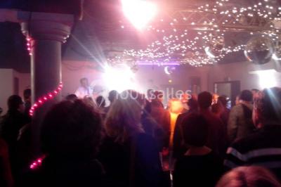 Groupe de personnes rassemblées dans une salle décorée avec des lumières et des guirlandes, lors d'une réception festive.