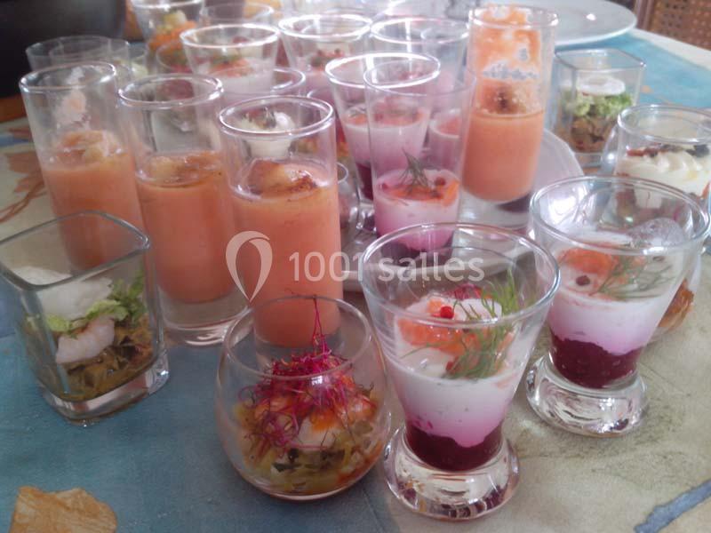 Assortiment de verrines colorées contenant des préparations salées et sucrées, présentées sur une table.