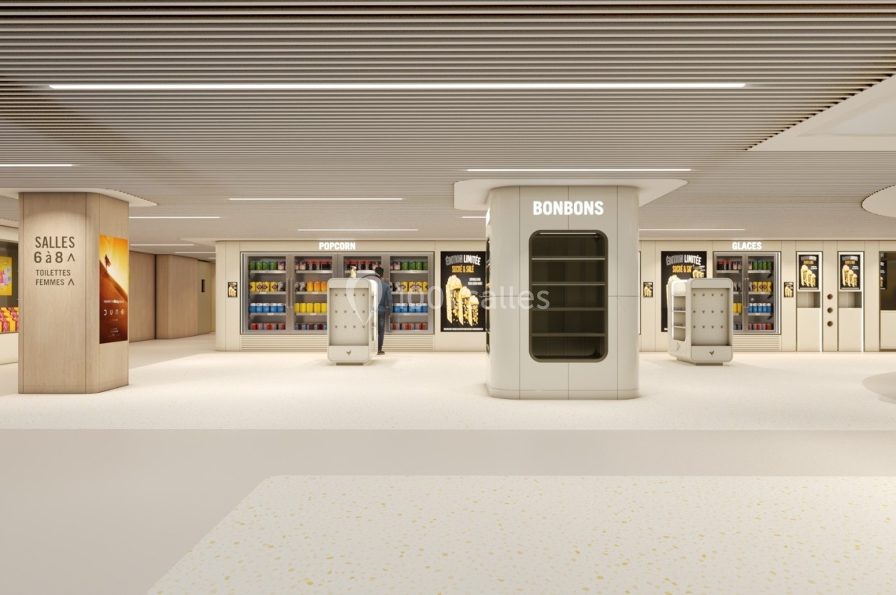 Vue d'un espace de vente moderne avec rayons de bonbons, pop-corn et glaces dans un hall lumineux.