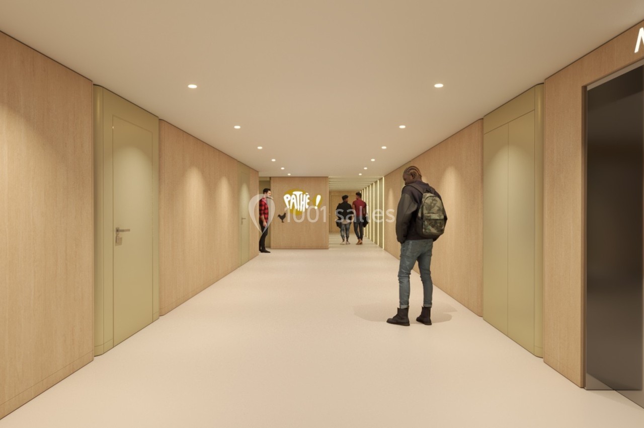 Couloir moderne avec murs en bois clair, éclairage encastré, portes latérales et personnes marchant ou discutant.