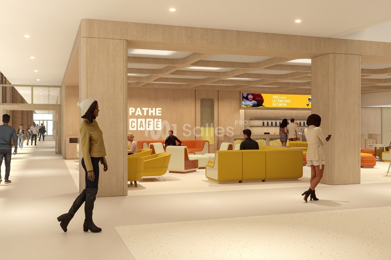 Vue d'un espace moderne avec des sièges jaunes, un café Pathé et des personnes discutant ou se déplaçant.