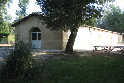 Miniature Location salle Beaucaire (Gard) - Le Fer à Cheval #5 Des enfants et des adultes préparent des poneys avec des selles dans un espace herbeux entouré d'arbres.