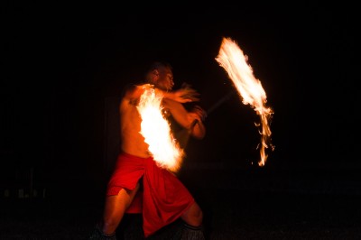 Un artiste jongle avec du feu dans l'obscurité, créant des motifs lumineux en mouvement.