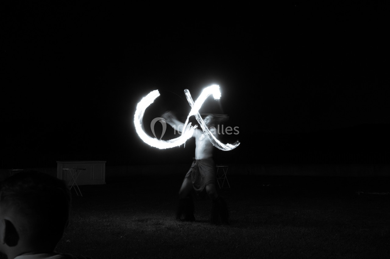 Un artiste jongle avec du feu dans l'obscurité, créant des motifs lumineux en mouvement.