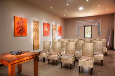 Salle de réunion avec table en bois, chaises en osier, bouteilles d'eau et fenêtre donnant sur un paysage verdoyant.