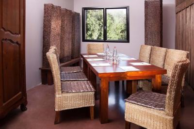 Salle de réunion avec table en bois, chaises en osier, bouteilles d'eau et fenêtre donnant sur un paysage verdoyant.