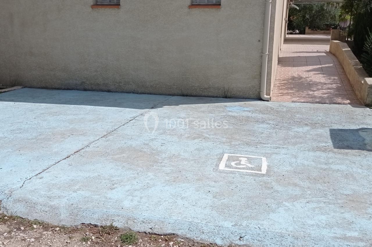Deux places de stationnement réservées aux personnes handicapées, marquées au sol devant un bâtiment beige.
