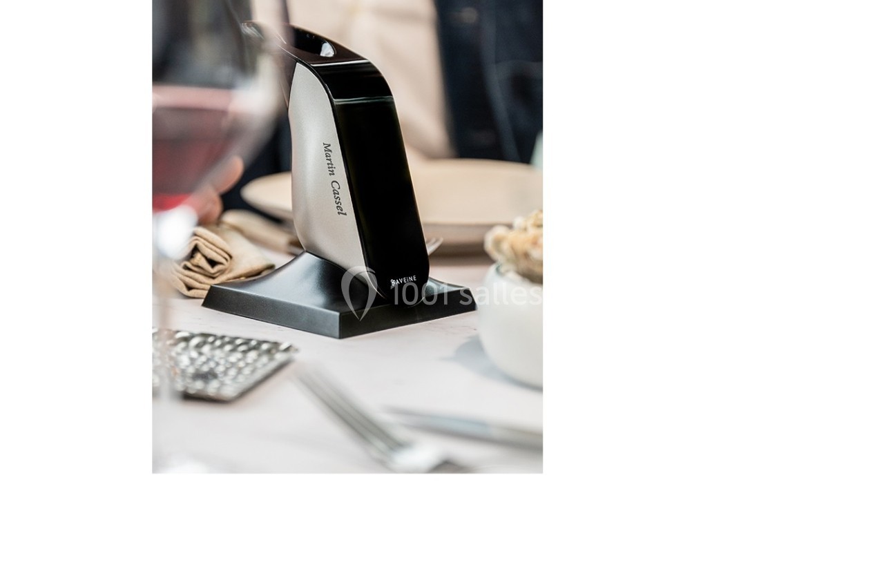 Appareil électrique noir et argent sur une table dressée, entouré de couverts et d'un verre de vin rouge.