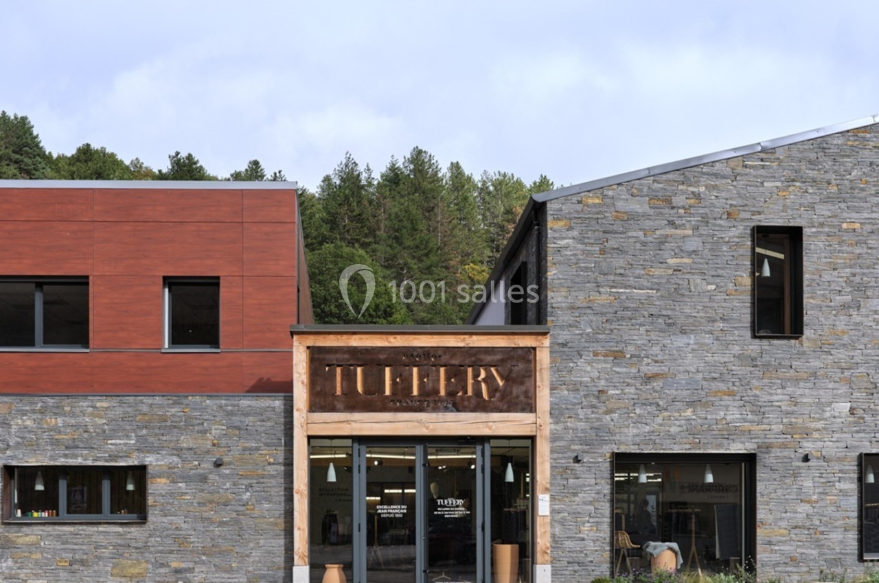 Façade d'un bâtiment moderne en pierre et bois avec une entrée vitrée et l'inscription ’Tuilery’.