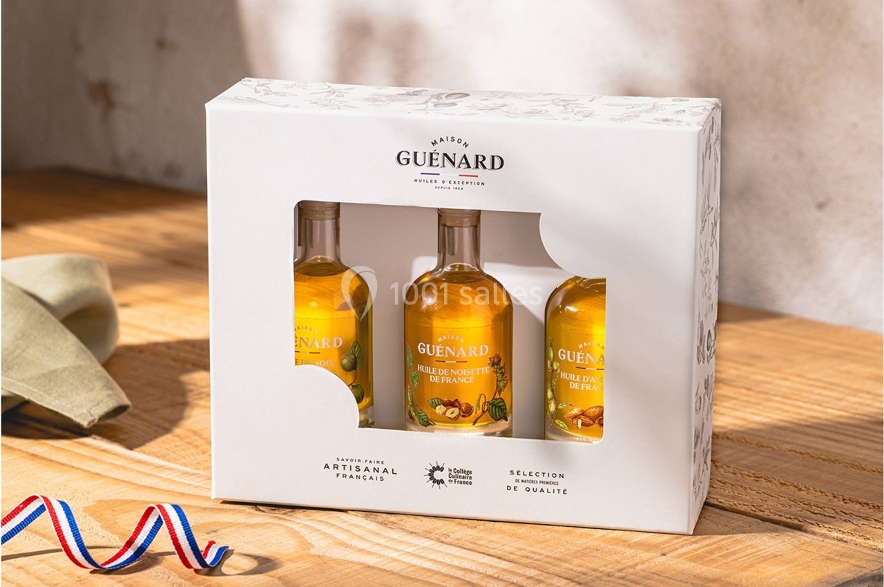 Coffret de trois bouteilles d'huiles artisanales françaises sur une table en bois, éclairé par une lumière naturelle.