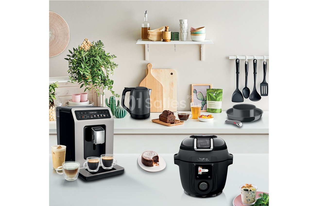 Cuisine moderne avec cafetière, autocuiseur, bouilloire, ustensiles suspendus et plan de travail décoré.